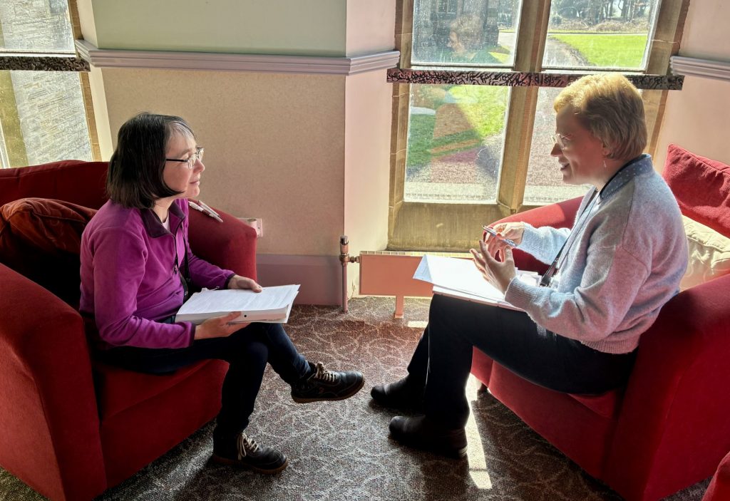 Two LCT students sit in armchairs having a conversation.